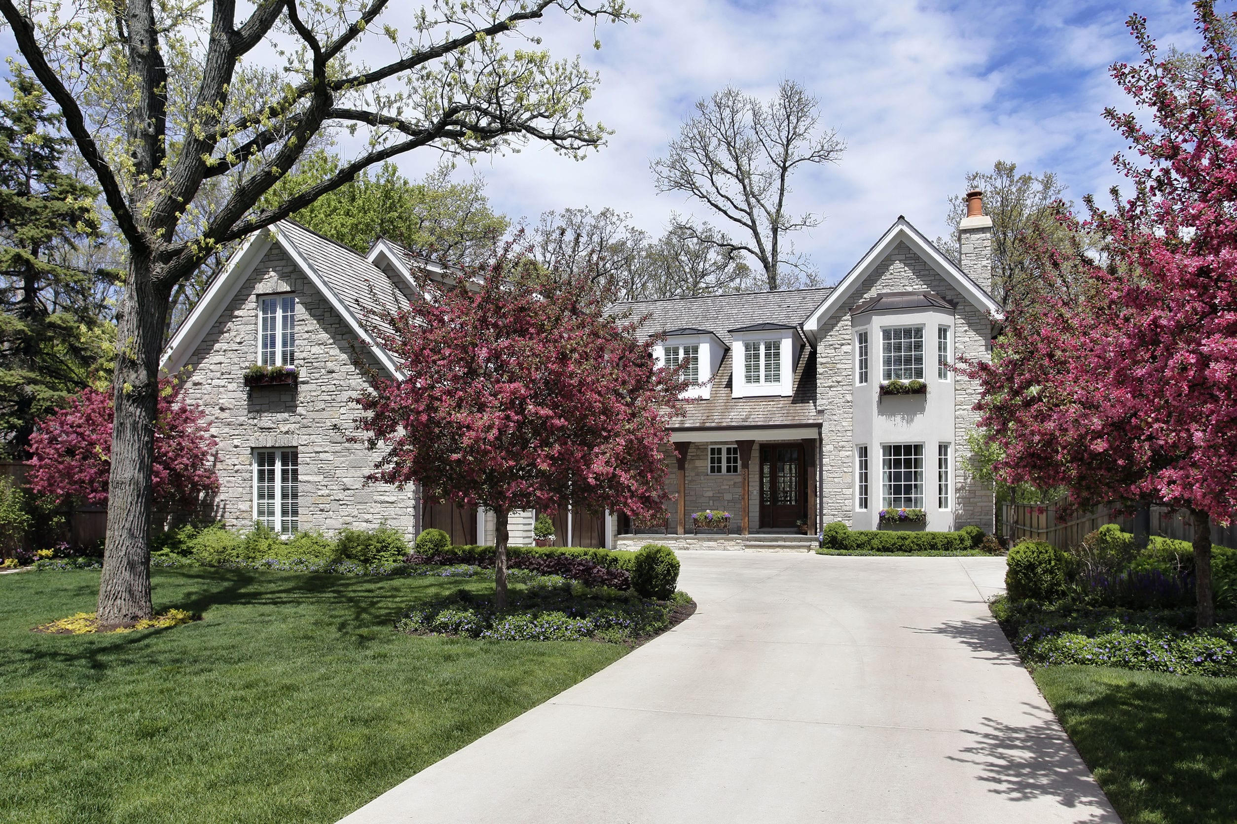 33458575 - stone home in suburbs with flowering trees stone home in suburbs with flowering trees